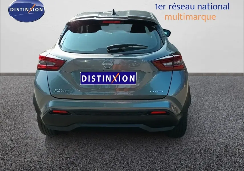 Vue arrière d'un Nissan Juke hybride gris squale métal 2025 avec logo et feux arrière distinctifs visibles.