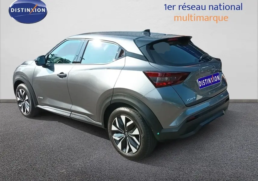 Vue 3/4 arrière droite du Nissan Juke hybride gris squale métal avec jantes distinctives et vitres teintées.