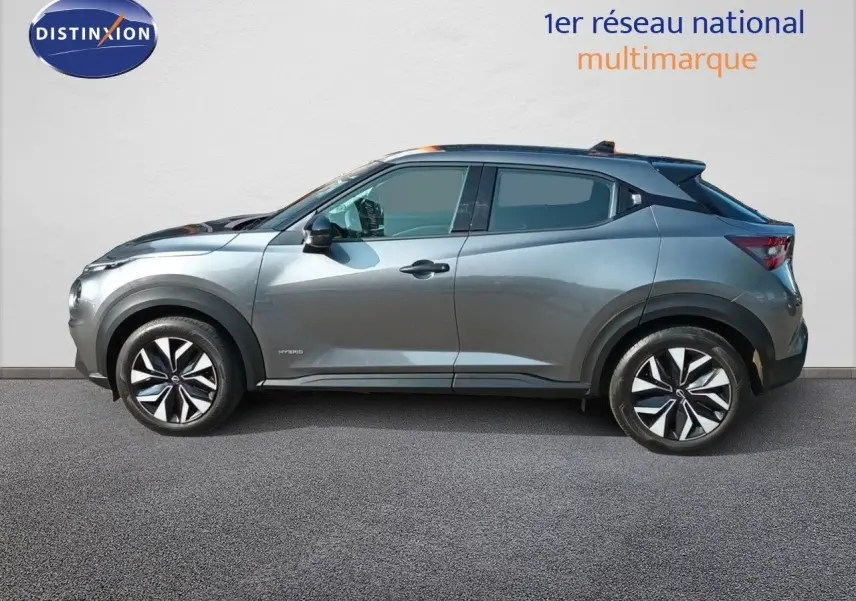 Profil droit du Nissan Juke Hybrid 143ch Acenta 2025 en gris squale métal avec jantes distinctives bicolores.