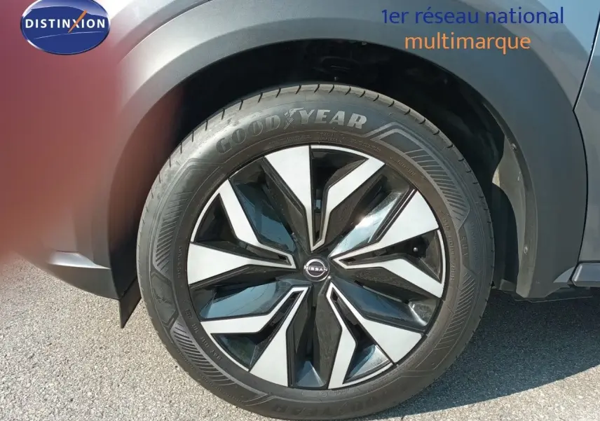 Gros plan sur la roue avant droite du Nissan Juke Hybrid 2025 en gris squale métal avec jante noire et argentée.