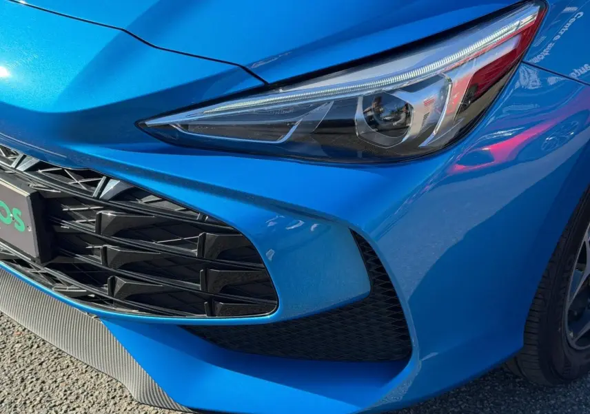 Gros plan sur l'avant droit du MG3 1.5 Hybrid+ 195ch Comfort en Como Blue métallisé, mettant en valeur le phare et la calandre.