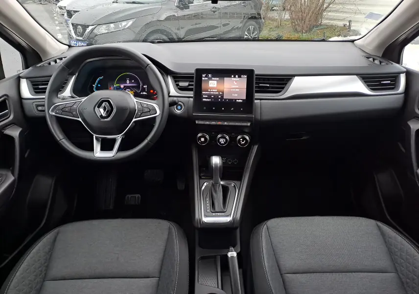 Vue intérieure avant du tableau de bord et volant noir du Renault Captur 1.6 E-TECH Hybrid avec écran tactile central.
