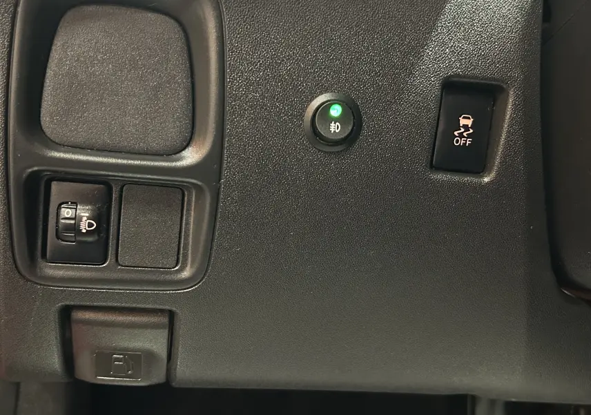 Vue rapprochée du tableau de bord noir de la Citroën C1 rouge, montrant les commandes d’éclairage et de stabilité.