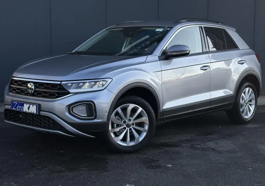 Volkswagen T-Roc 1.5 TSI argent Pyrite en 3/4 avant droit, avec jantes alliage et calandre noire distinctive.