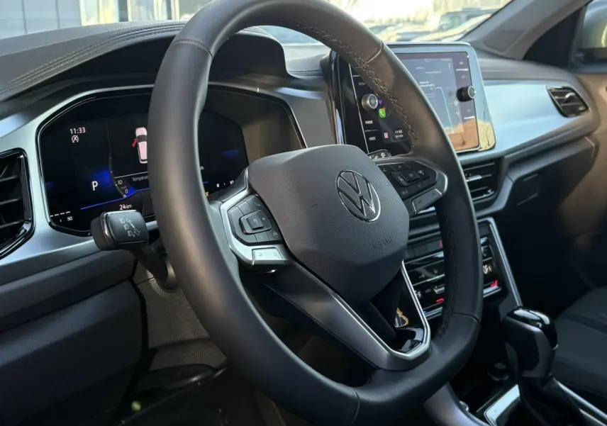 Vue rapprochée de l'intérieur du Volkswagen T-Roc 2025, volant cuir multifonction et écran tactile central visibles.