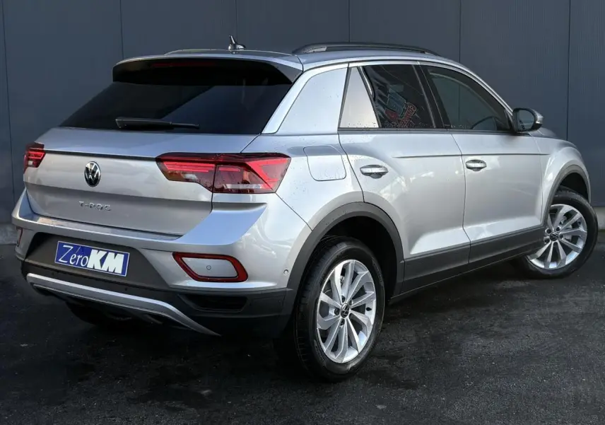 Volkswagen T-Roc argent Pyrite en 3/4 arrière droit, avec feux LED et jantes alliage visibles.