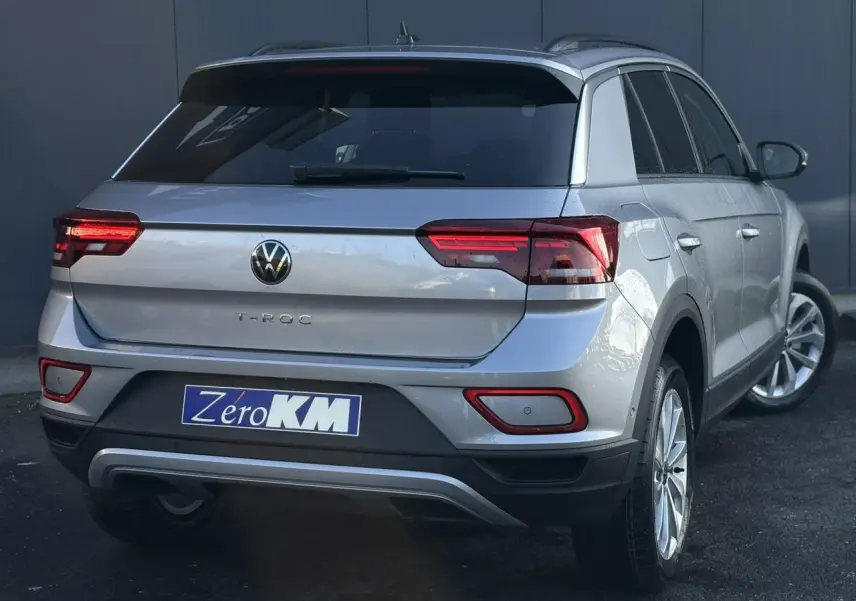 Vue 3/4 arrière droite d'un Volkswagen T-Roc argent pyrite 2025 avec feux arrière LED et jantes alliage.