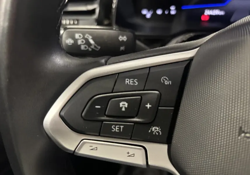 Gros plan sur les commandes du volant cuir multifonctions du Volkswagen Taigo 2023, boutons noirs et argentés.