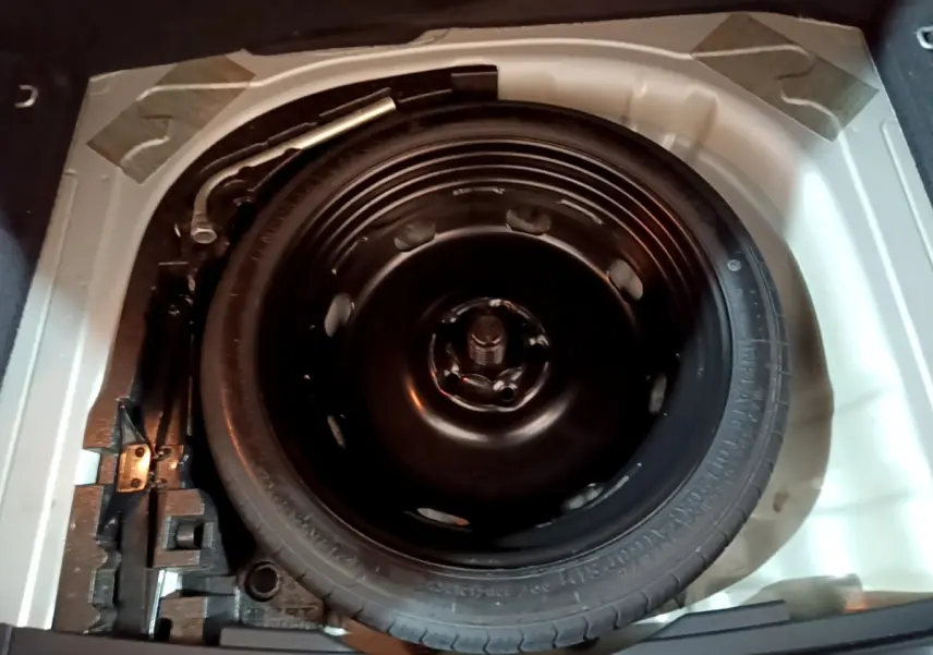 Vue plongeante sur la roue de secours galette noire dans le coffre du SEAT Ateca gris clair 2022.