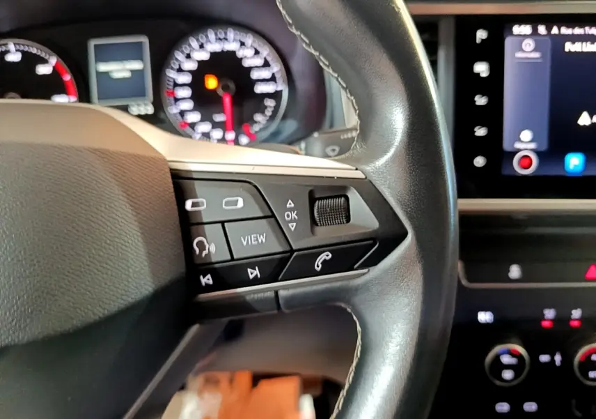 Gros plan sur le volant en cuir noir avec commandes multifonctions, tableau de bord et écran tactile du SEAT Ateca gris clair 2022.