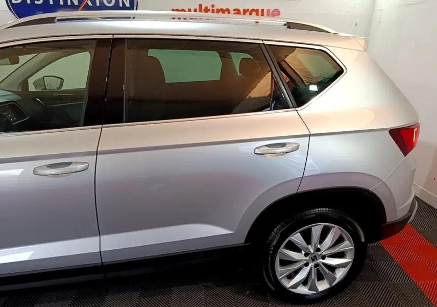 Vue latérale droite d'un SEAT Ateca gris clair, mettant en valeur la porte arrière et la roue avec jante alu.