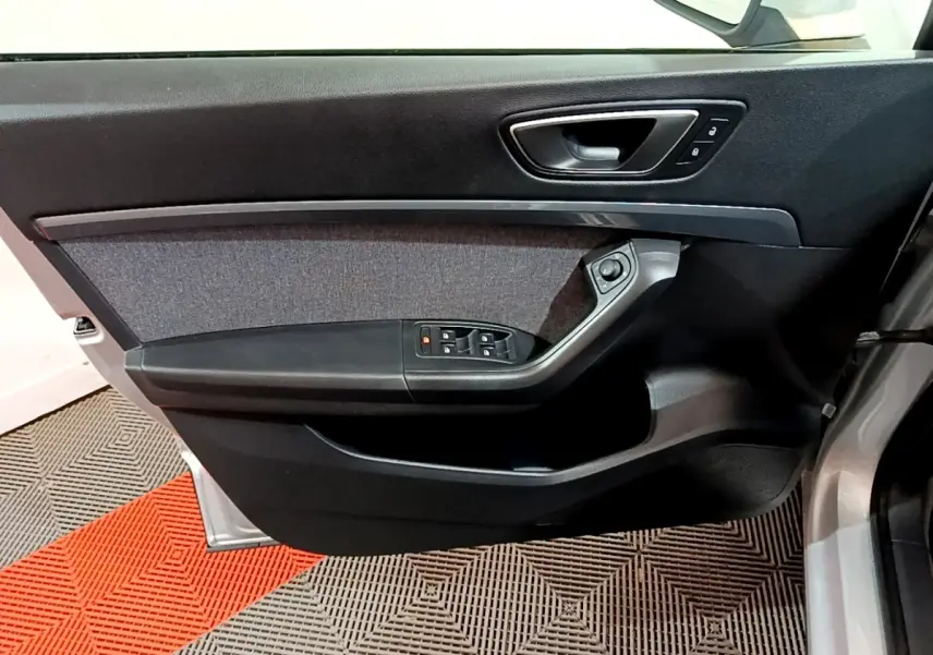 Vue intérieure côté gauche de la porte avant d'un SEAT Ateca gris clair avec commandes de vitres et verrouillage.