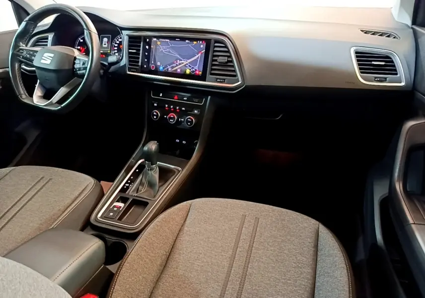 Vue intérieure avant du SEAT Ateca 2022, tableau de bord noir avec écran tactile de navigation et sièges tissu gris.
