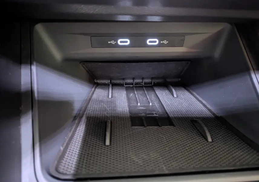 Gros plan sur la zone de recharge sans fil et ports USB lumineux dans l'habitacle noir du CUPRA Leon 2025.