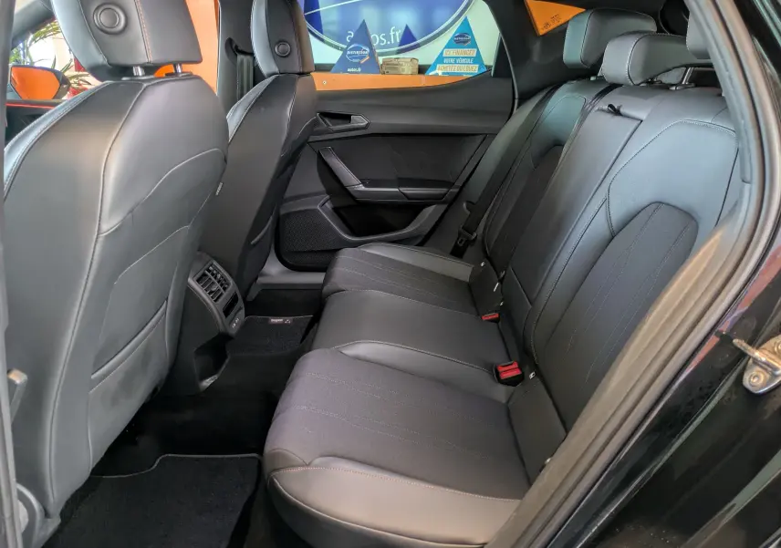 Vue intérieure côté droit des sièges arrière en cuir et tissu noir d'une CUPRA Leon 2025 avec portières ouvertes.