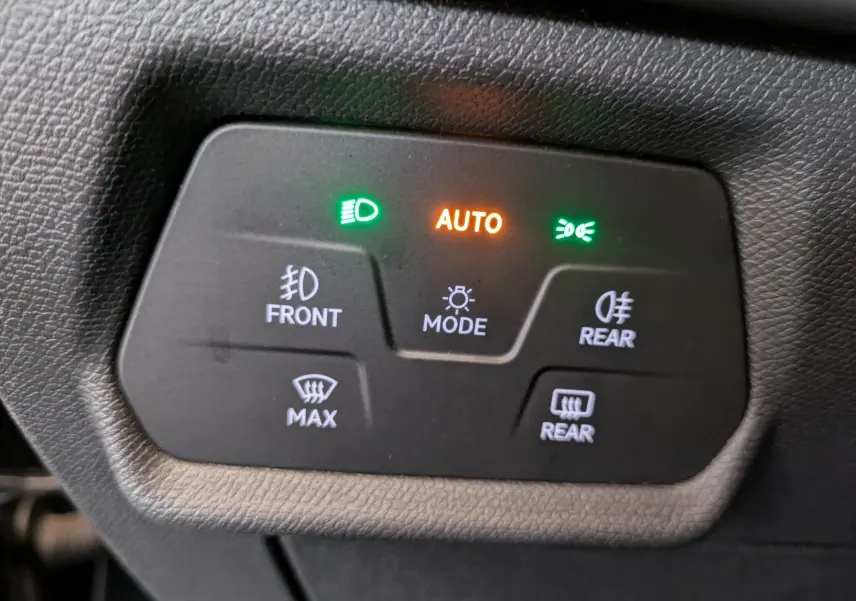 Gros plan sur le panneau de commande des feux et dégivrage d’une CUPRA Leon 2.0TDI noire, avec mode automatique activé.