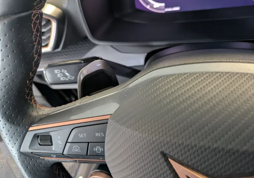 Gros plan sur le volant noir à surpiqûres cuivrées du Cupra Leon 2.0 TDI 150 DSG7 avec commandes intégrées.