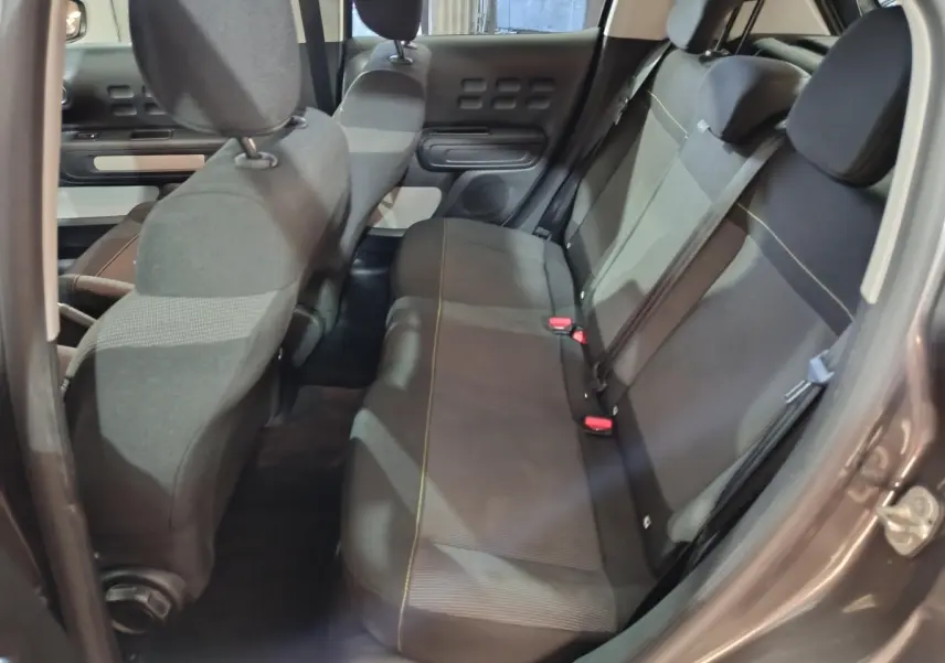 Vue intérieure côté droit sur la banquette arrière gris foncé de la Citroën C3 2024 avec sièges tissu et ceintures visibles.