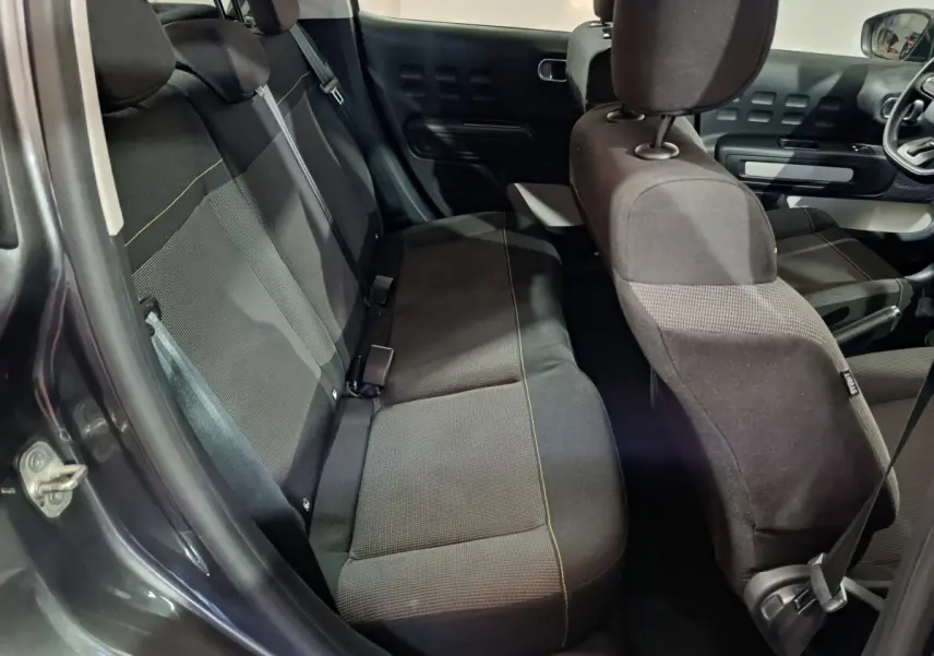Vue intérieure côté arrière gauche de la Citroën C3 2024 gris foncé, montrant les sièges tissu et la porte ouverte.