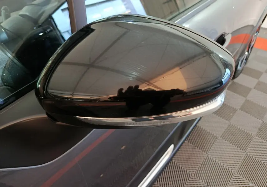 Gros plan sur le rétroviseur droit noir brillant d’une Citroën C3 gris foncé, avec clignotant intégré visible.