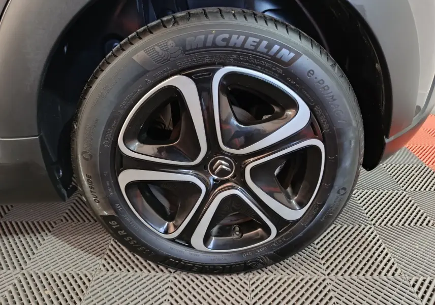 Gros plan sur la roue avant droite d'une Citroën C3 gris foncé, avec jante noire et inserts argentés distinctifs.