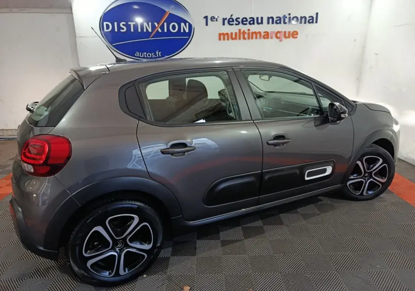 Vue latérale droite d'une Citroën C3 BlueHDi 100 BVM PLUS gris foncé avec jantes alliage et protections latérales noires.