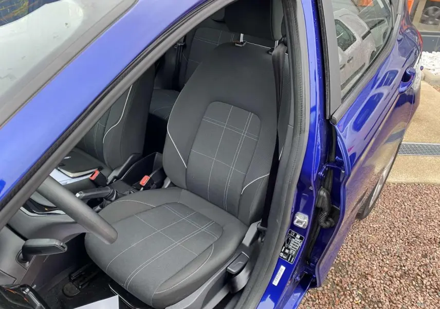 Vue intérieure côté conducteur d'une Ford Fiesta 2017 bleu foncé, avec siège tissu gris à motifs discrets.