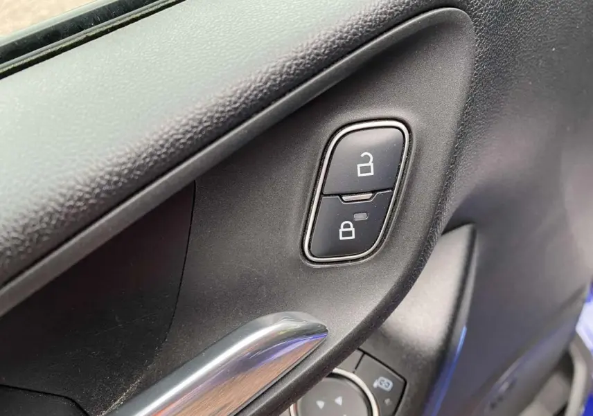 Détail intérieur de la porte côté conducteur de la Ford Fiesta 2017 bleu foncé, avec commandes de verrouillage et poignée chromée.