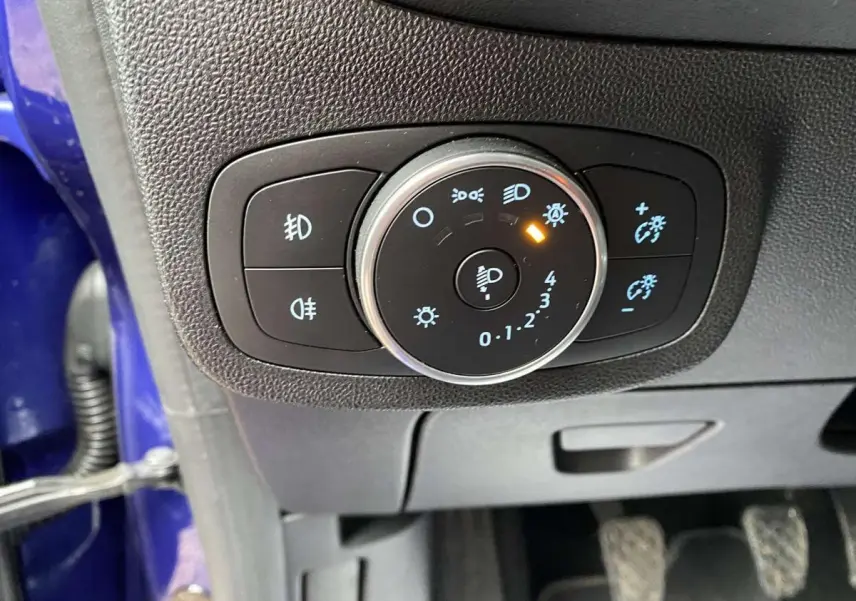Gros plan sur la commande d'éclairage intérieur d'une Ford Fiesta 2017 bleu foncé, avec réglage des phares activé.