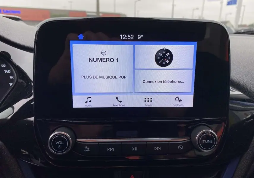 Écran tactile central de la Ford Fiesta 2017 bleu foncé affichant radio et connexion téléphone, vue de face intérieure.