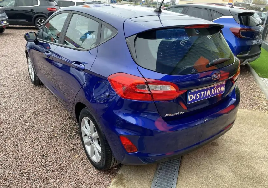Vue 3/4 arrière gauche d'une Ford Fiesta bleu foncé 2017 avec feux arrière allongés et jantes argentées.