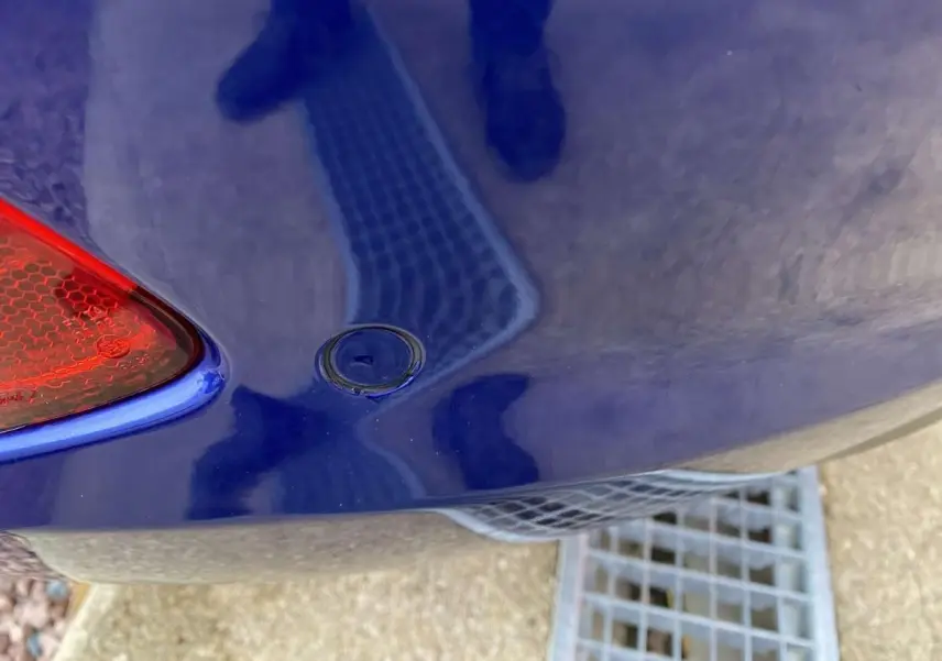Gros plan sur l'angle arrière gauche d'une Ford Fiesta bleu foncé 2017, avec feu arrière et capteur de recul visibles.
