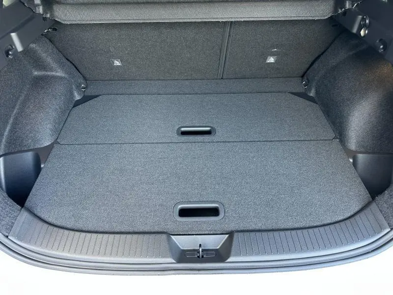 Coffre ouvert vu de l'arrière d'un Nissan Qashqai Hybrid e-POWER blanc nacré avec plancher de chargement plat et compartiments dissimulés.