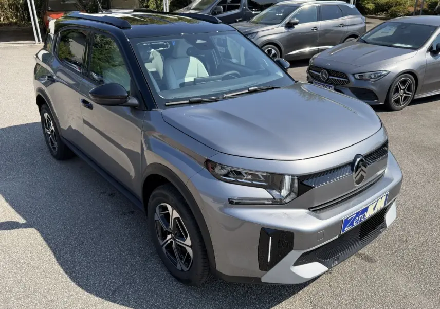 Citroën C3 Aircross gris clair vue 3/4 avant droit, avec toit noir et jantes distinctives, en extérieur sur parking.