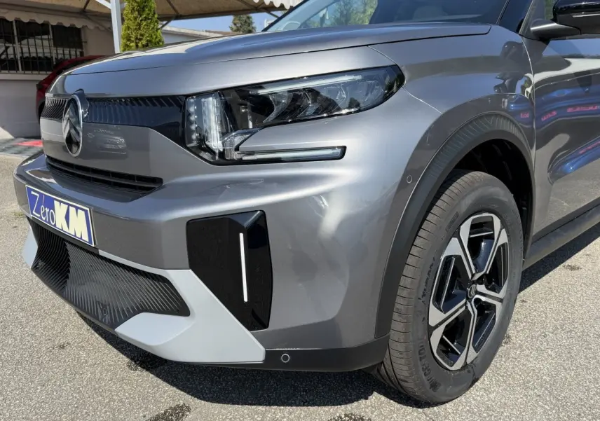Vue 3/4 avant droit d'une Citroën C3 Aircross gris clair avec phares LED et jantes noires distinctives.