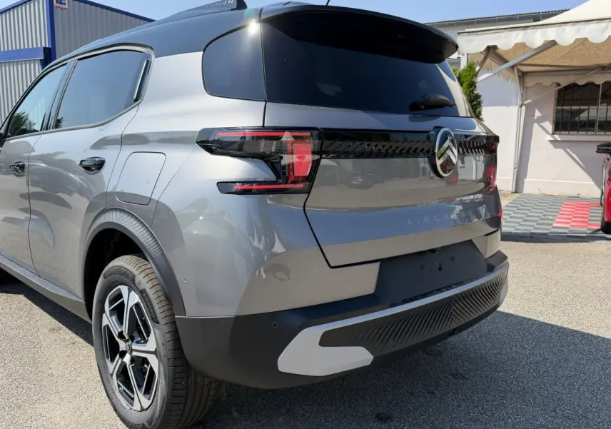 Vue 3/4 arrière droite d'un Citroën C3 Aircross gris clair avec feux LED et jantes distinctives.