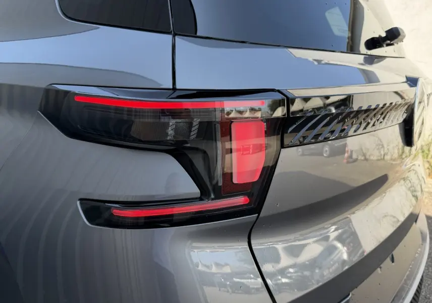 Gros plan sur le feu arrière droit gris clair du Citroën C3 Aircross hybride 2026 avec détails noirs et rouges distinctifs.