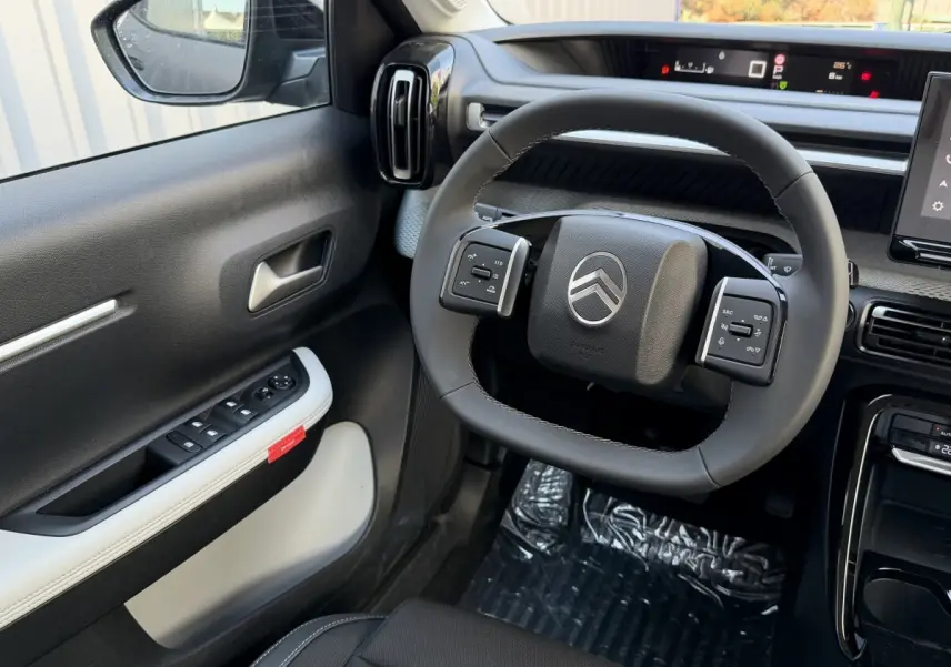 Vue intérieure côté conducteur du Citroën C3 Aircross gris clair, volant cuir multifonctions et tableau de bord numérique.