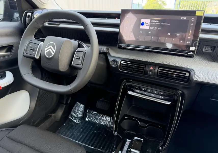 Vue intérieure de face du tableau de bord et volant cuir noir de la Citroën C3 Aircross hybride 2026 avec écran tactile 10,25 pouces.