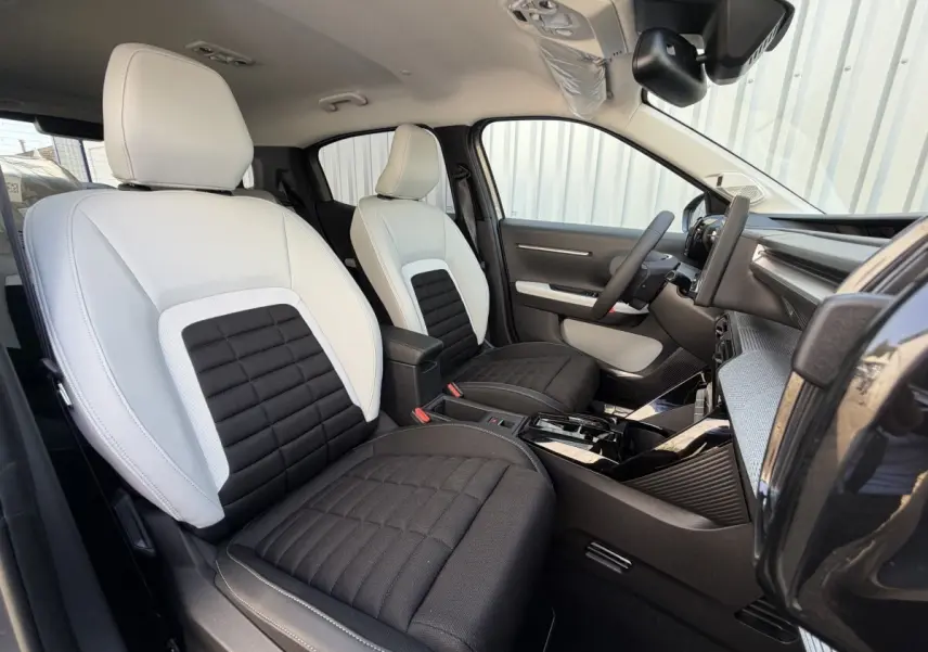 Vue intérieure côté conducteur de la Citroën C3 Aircross 2026, sièges bicolores noir et blanc avec tableau de bord moderne.