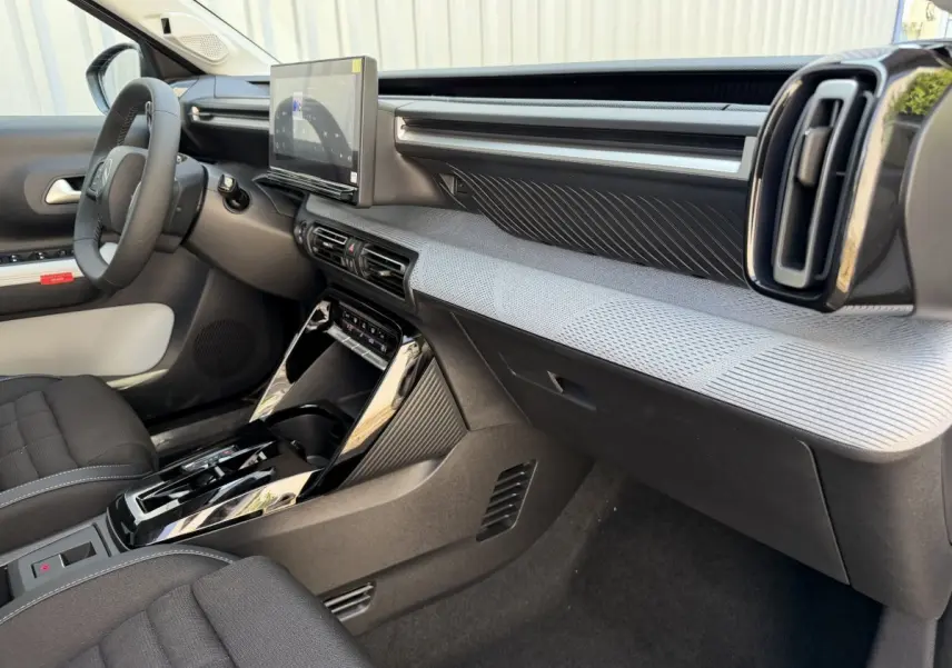 Vue intérieure côté passager du tableau de bord gris clair et noir du Citroën C3 Aircross hybride avec écran tactile central.