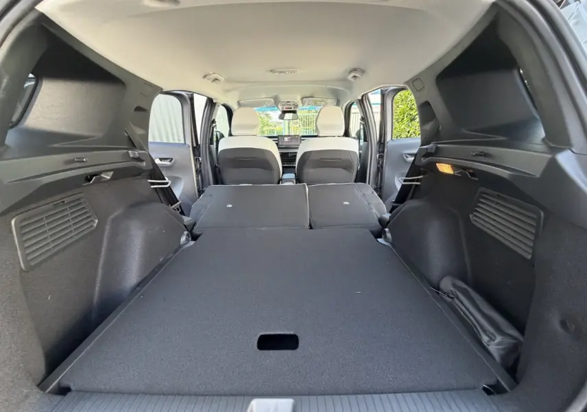 Vue intérieure du coffre avec banquette arrière rabattue du Citroën C3 Aircross gris clair, montrant l'espace de chargement plat.