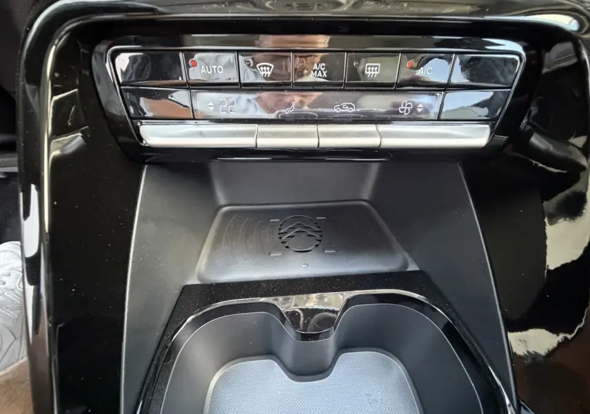 Vue rapprochée de la console centrale noire du Citroën C3 Aircross hybride, avec zone de recharge par induction visible.