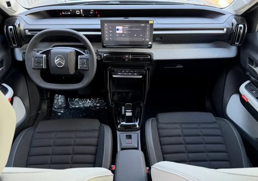 Vue intérieure avant de la Citroën C3 Aircross hybride 2026, tableau de bord moderne avec écran tactile central et volant cuir noir.