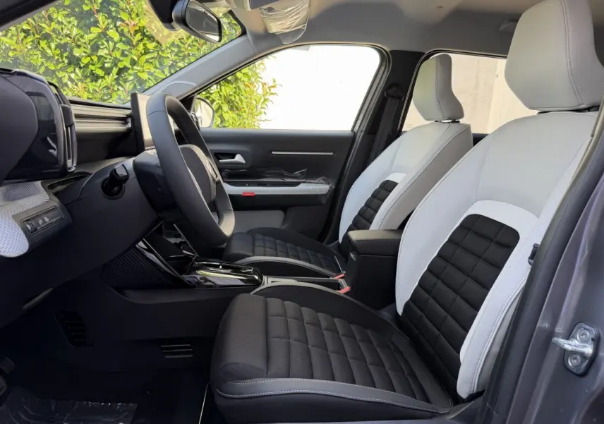 Vue intérieure côté conducteur de la Citroën C3 Aircross gris clair, sièges bicolores noir et blanc avec volant cuir multifonctions.