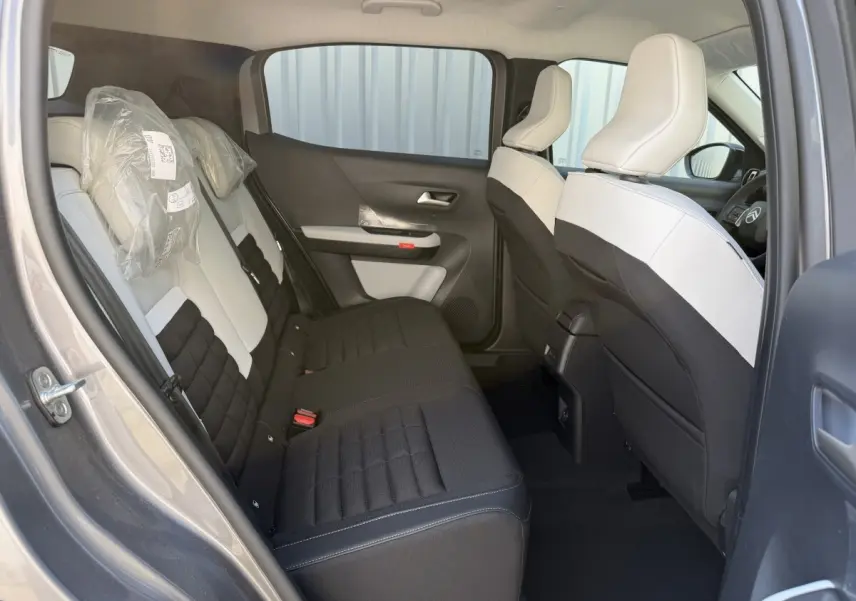 Vue intérieure arrière côté gauche du Citroën C3 Aircross gris clair, sièges bicolores noir et blanc avec appuie-têtes protégés.