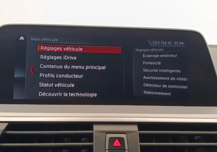 Écran central du tableau de bord d’une BMW X3 gris clair affichant le menu des réglages véhicule.