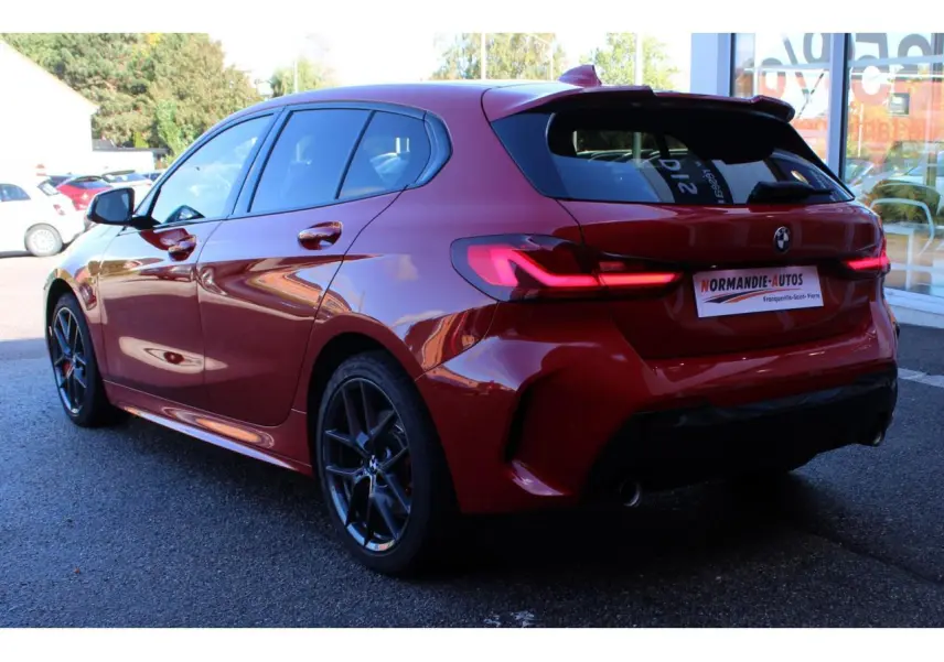 BMW Série 1 118d Edition M Sport Pro vue 3/4 arrière côté gauche en Melbourne Rot métallisé avec jantes gris ferric.
