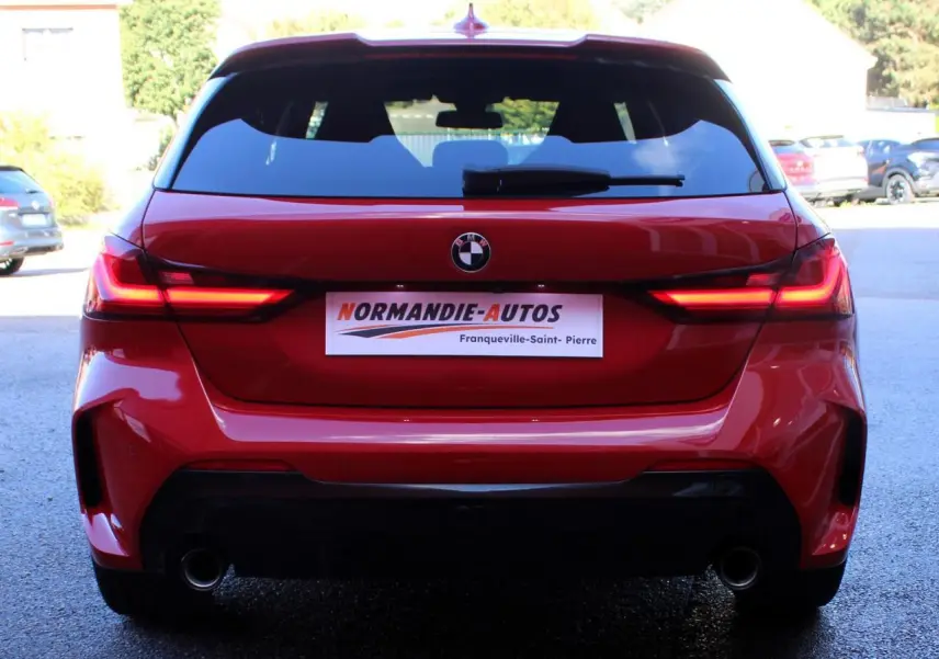 Vue arrière d'une BMW Série 1 118d rouge Melbourne avec feux LED allumés et double sortie d'échappement.