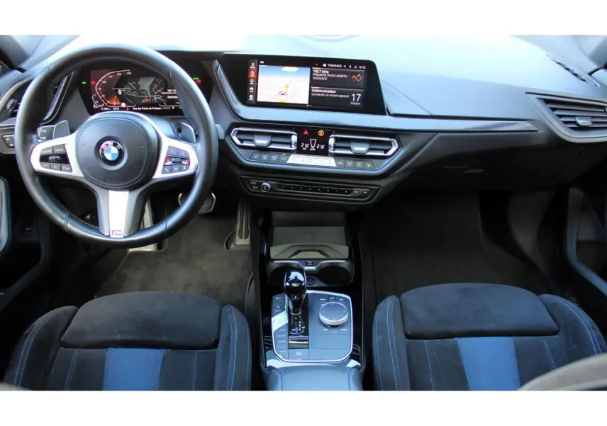 Vue intérieure avant de la BMW Série 1 118d Edition M Sport Pro, tableau de bord moderne avec écran tactile et volant M cuir.